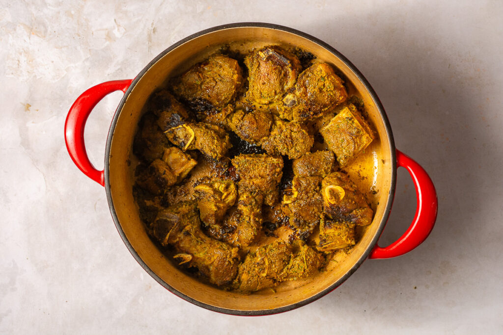 seared goat meat in a dutch oven
