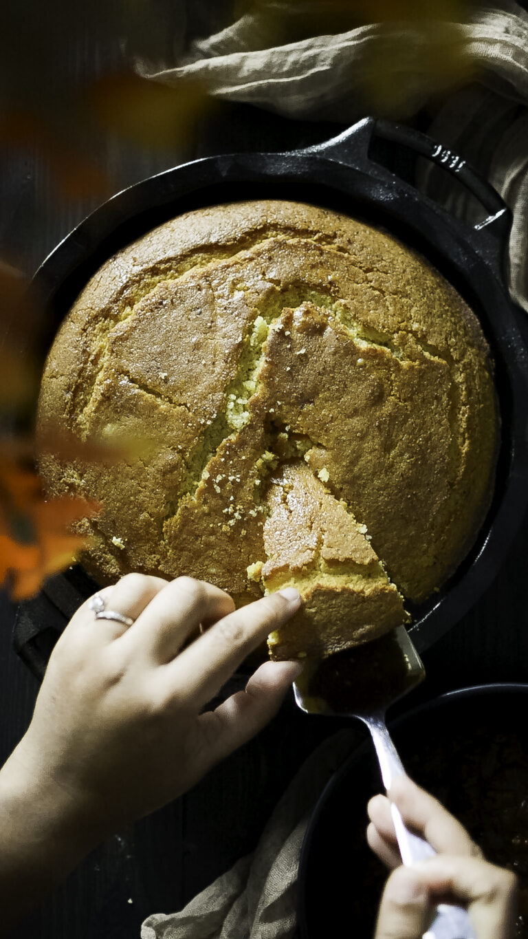 lodge skillet with cornbread being cut and slice being lifted out