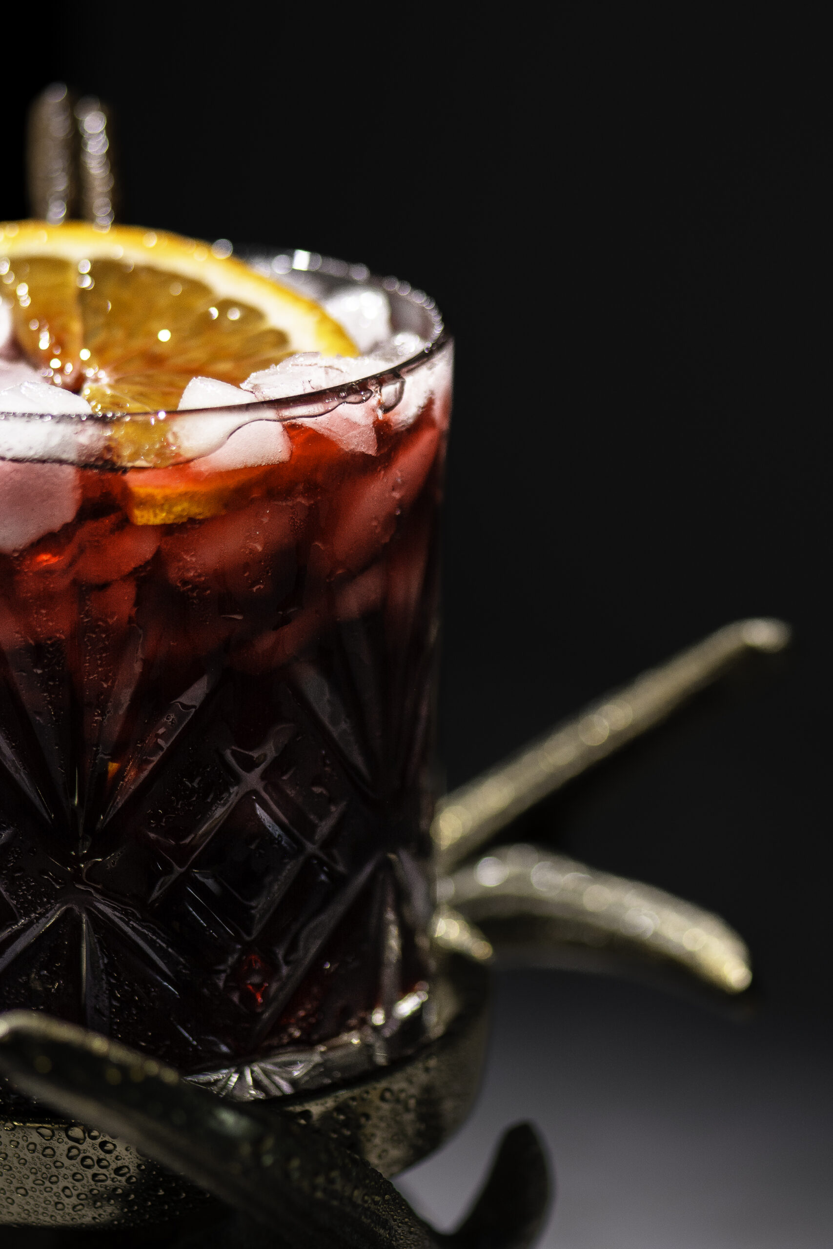 closeup of a glass of Jamaican sorrel drink garnished with a slice of orange and cinnamon stick in glass