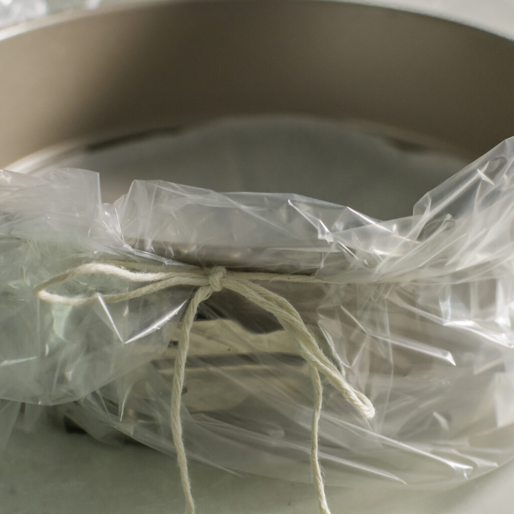springform pan prepared for water bath by securing oven bag to sidees with kitchen twine
