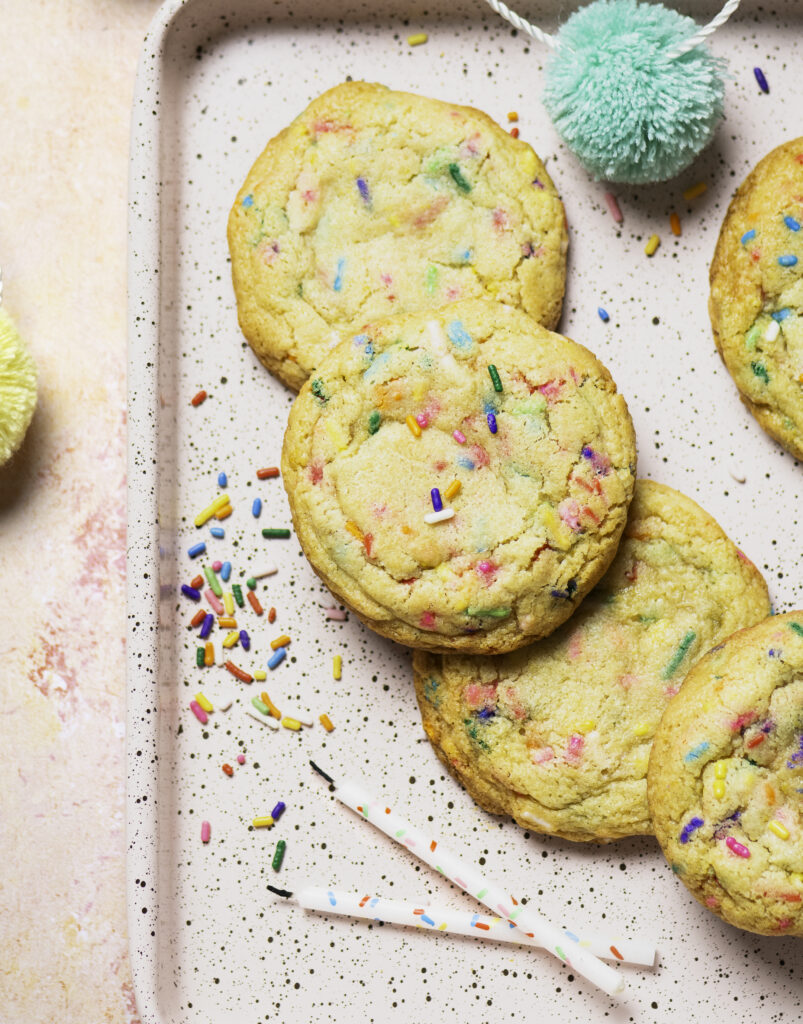 pink baking tray with 10 funfetti birthday cookies, 2 birthday candles and some sprinkles