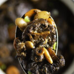 spoonful of braised Jamaican oxtail with butter beans, carrots and green onions