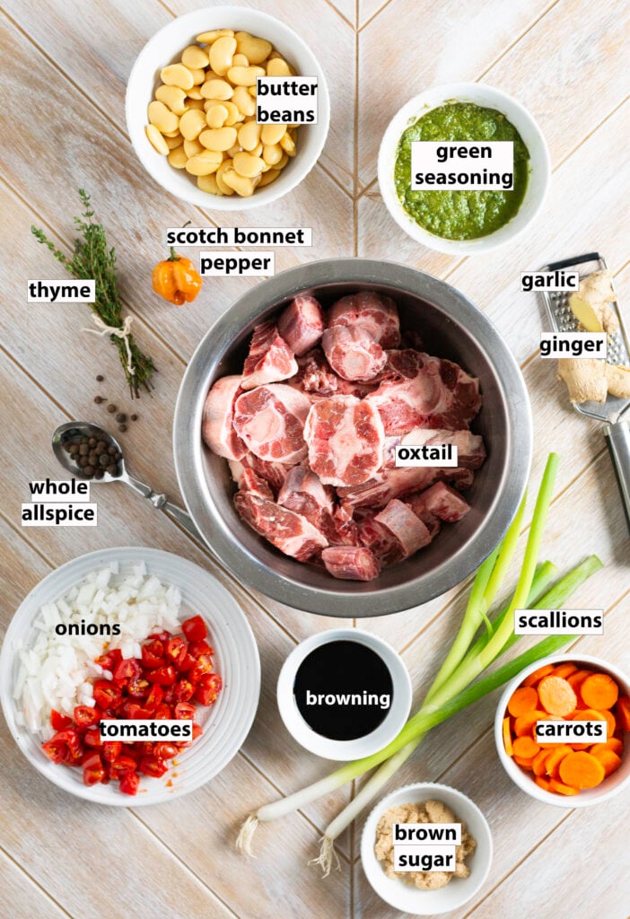 ingredients for braised Jamaican oxtail - oxtail, butter beans, green seasoning, garlic, ginger, scallions, sliced carrots, brown sugar, browning, diced tomatoes, diced yellow onions, whole allspice, thyme & orange scotch bonnet pepper