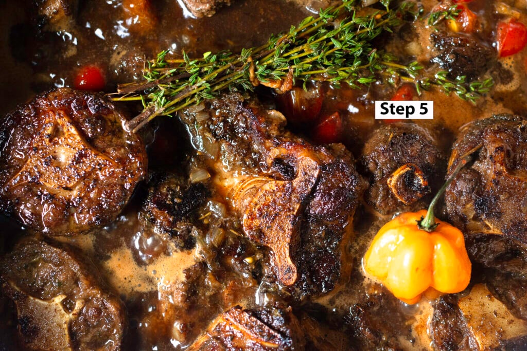 braising Jamaican oxtail with fresh herbs and scotch bonnet pepper