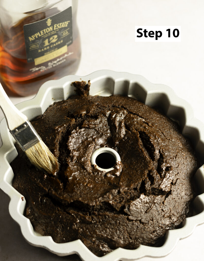 Jamaican black cake in a Bundt pan being brushed with Appleton 12-year rum