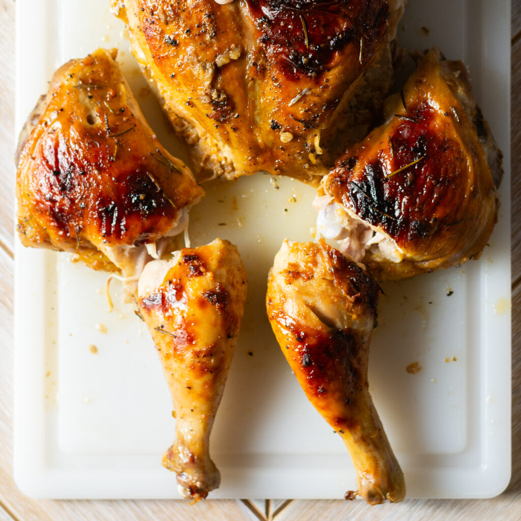 breaking apart a spatchcocked and whole roasted orange maple chicken