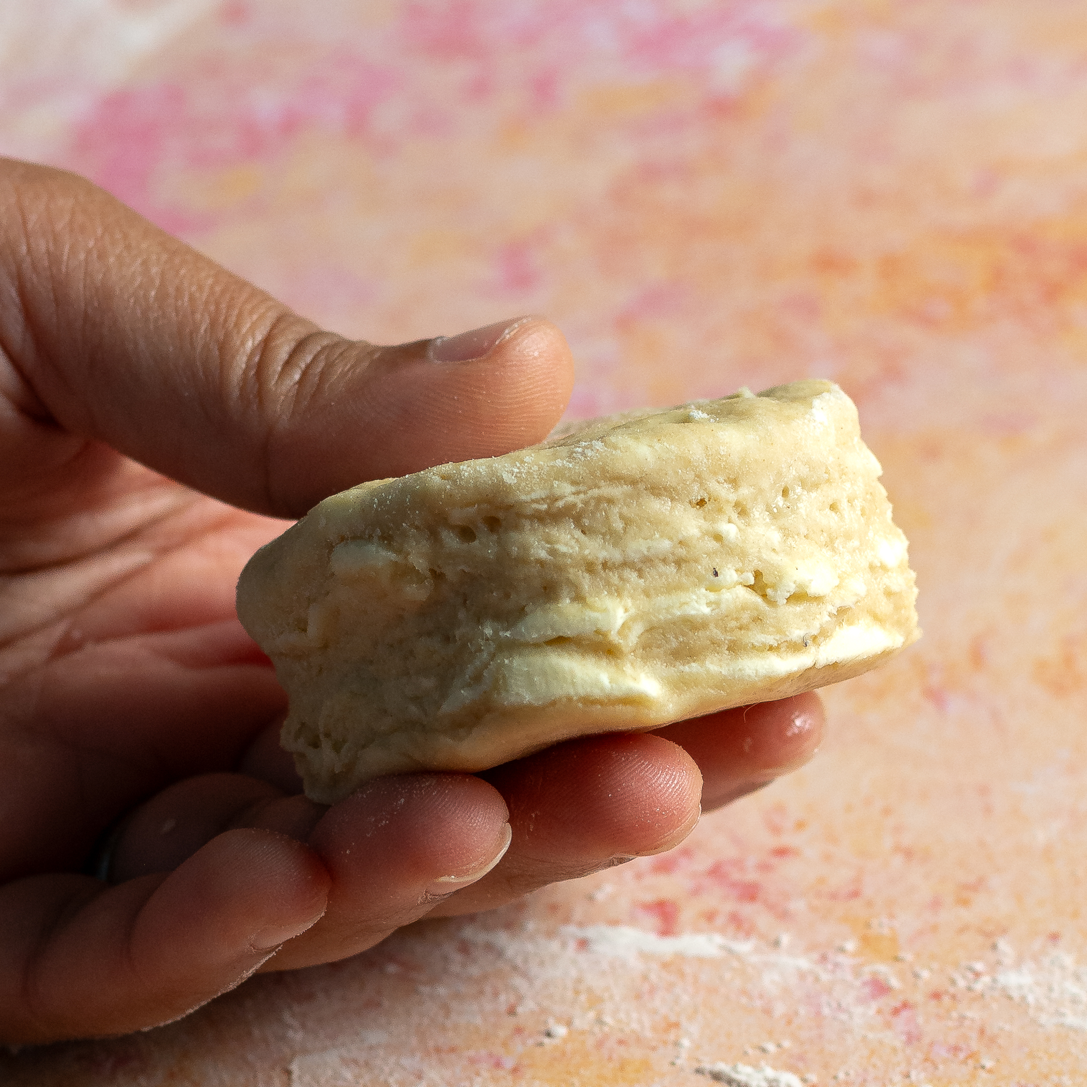 person holding biscuit dough cut into a round.