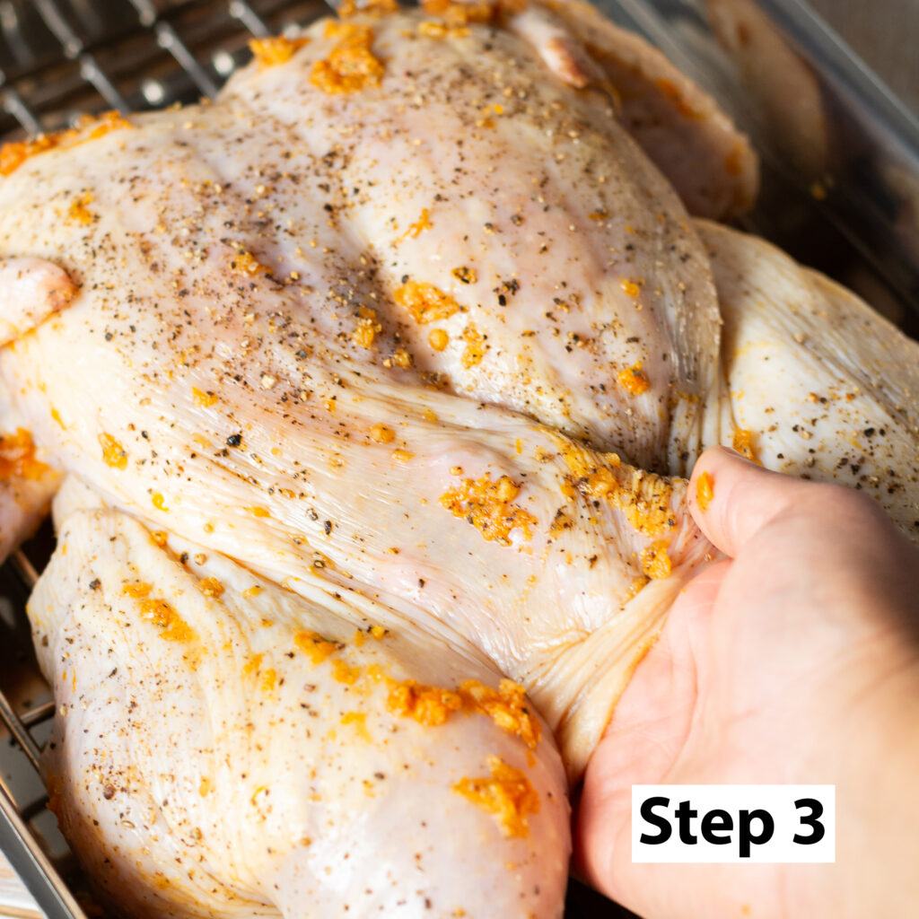 rubbing seasoning under a whole chicken to be whole roasted
