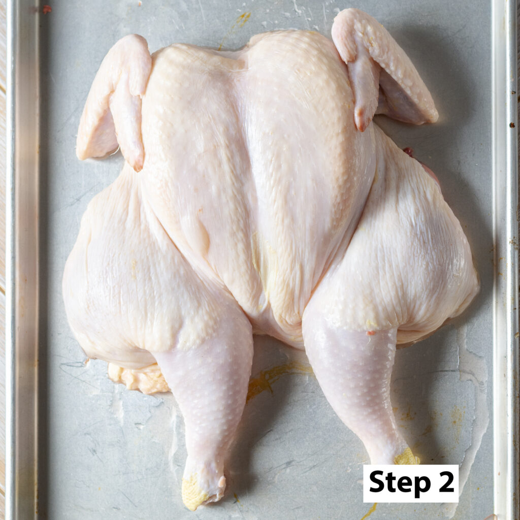a spatchcocked whole roaster chicken on a metal baking sheet