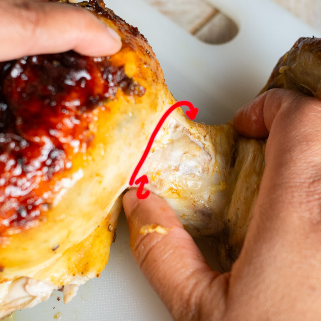 twisting the wing off a spatchcocked and whole roasted orange maple chicken