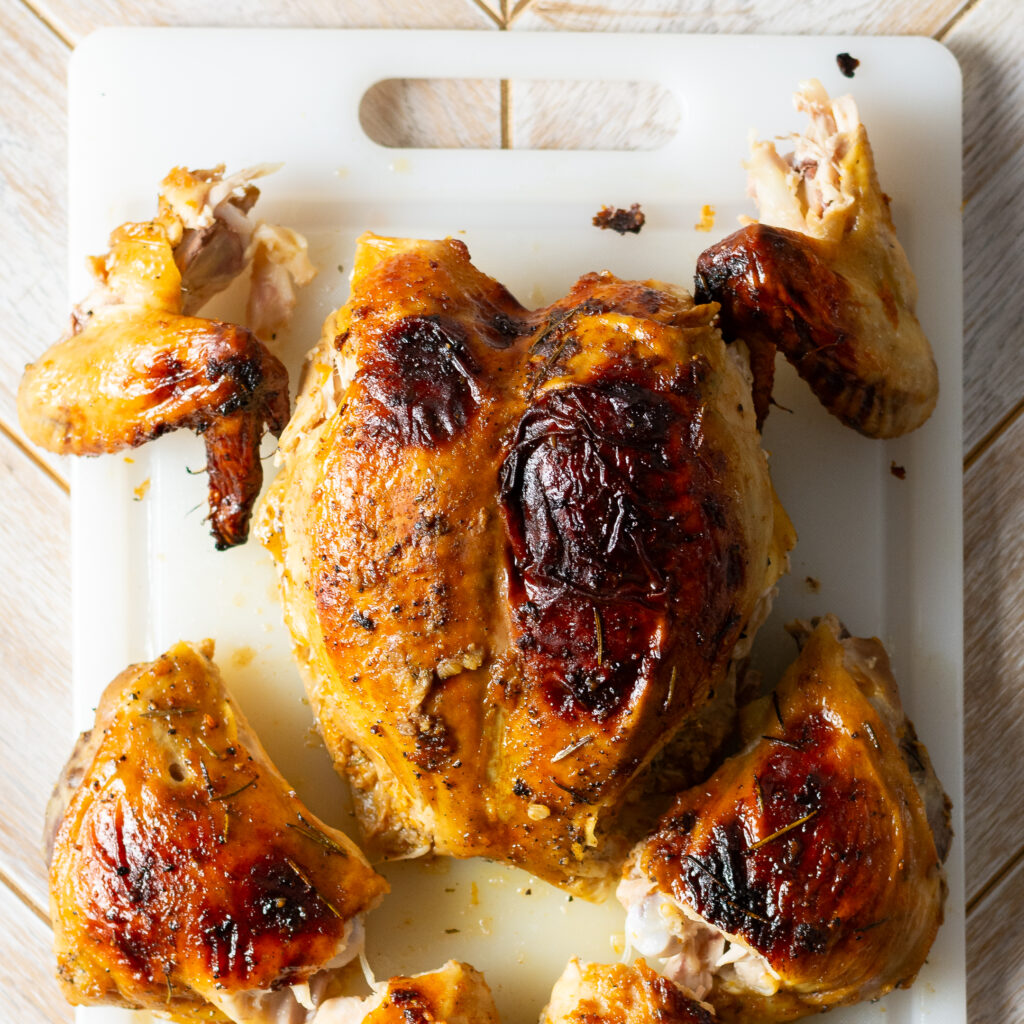 breaking apart a spatchcocked and whole roasted orange maple chicken