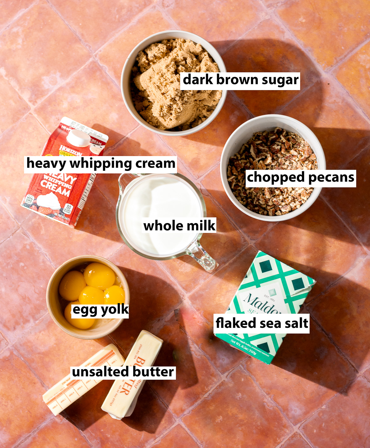 ingredients for homemade butter pecan ice cream - dark brown sugar, crushed pecans, flaked sea salt, whole milk, heavy cream, egg yolks, unsalted butter.