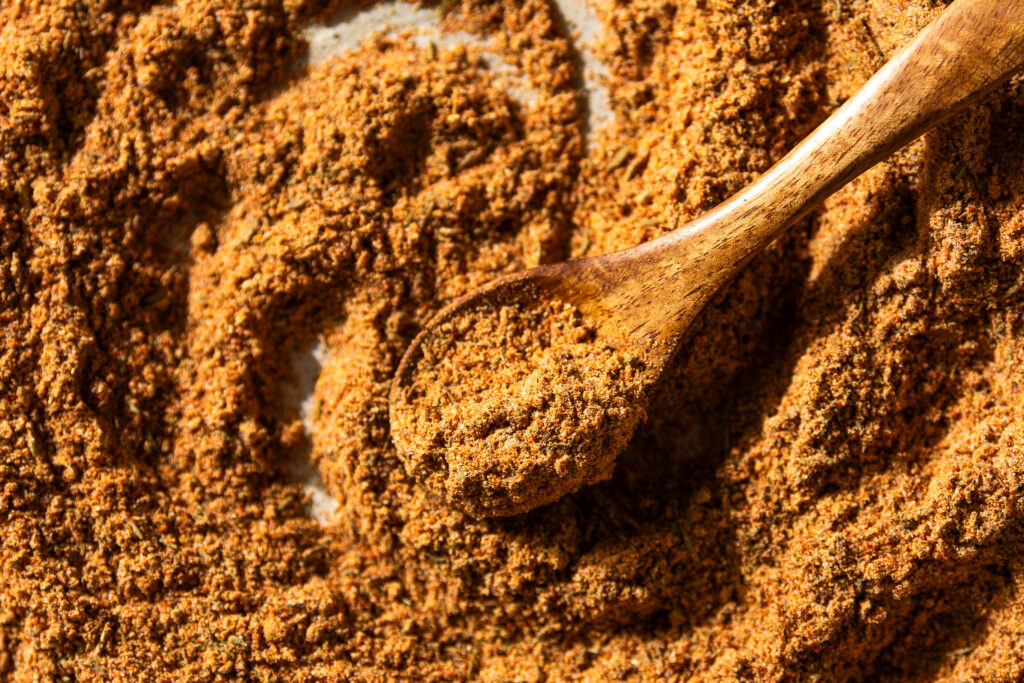 wooden spoon scooping homemade taco seasoning on a plate