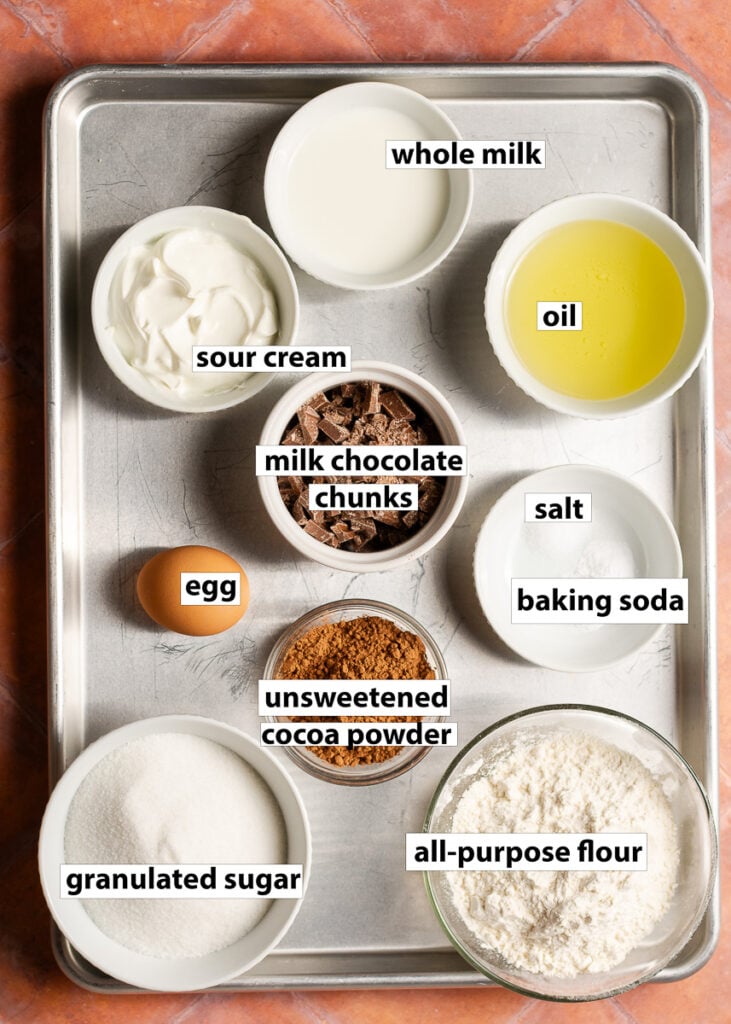 ingredients for small batch brownies - all-purpose flour, unsweetened cocoa powder, granulated sugar, baking soda, salt, egg, sour cream, whole milk & oil. Milk chocolate is optional.