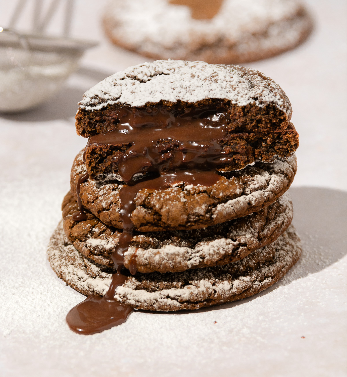 a stack of 4 chocolate lava cookies with the one on top broken in half and molten chocolate oozing out