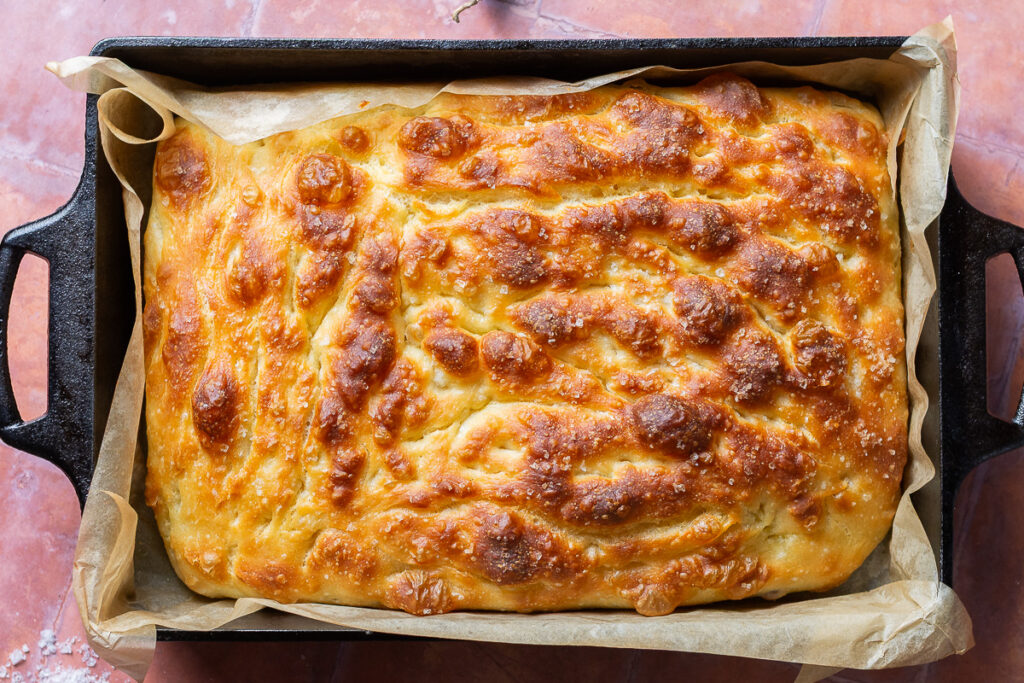 cassava focaccia in a cast iron pan lined with parchment paper