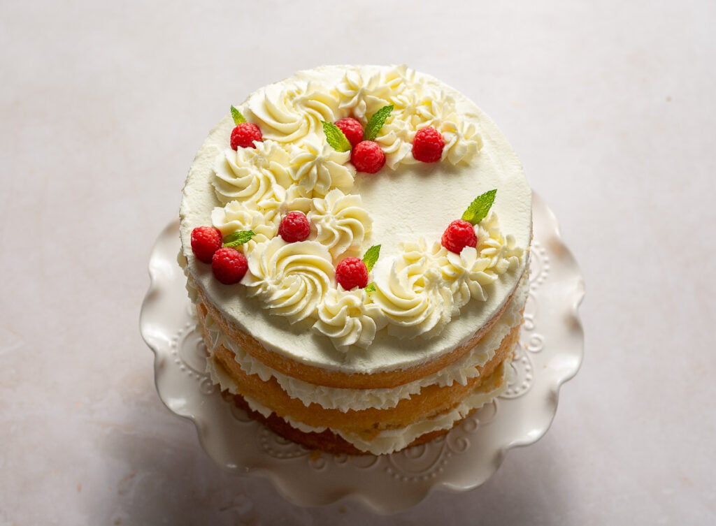naked 3-layer honey lemon cake topped with mascarpone whipped cream rosettes, fresh raspberries and mint leaves