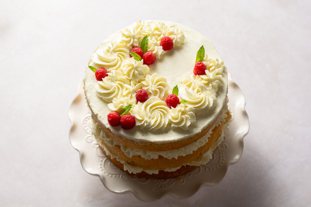 naked 3-layer honey lemon cake topped with mascarpone whipped cream rosettes, fresh raspberries and mint leaves