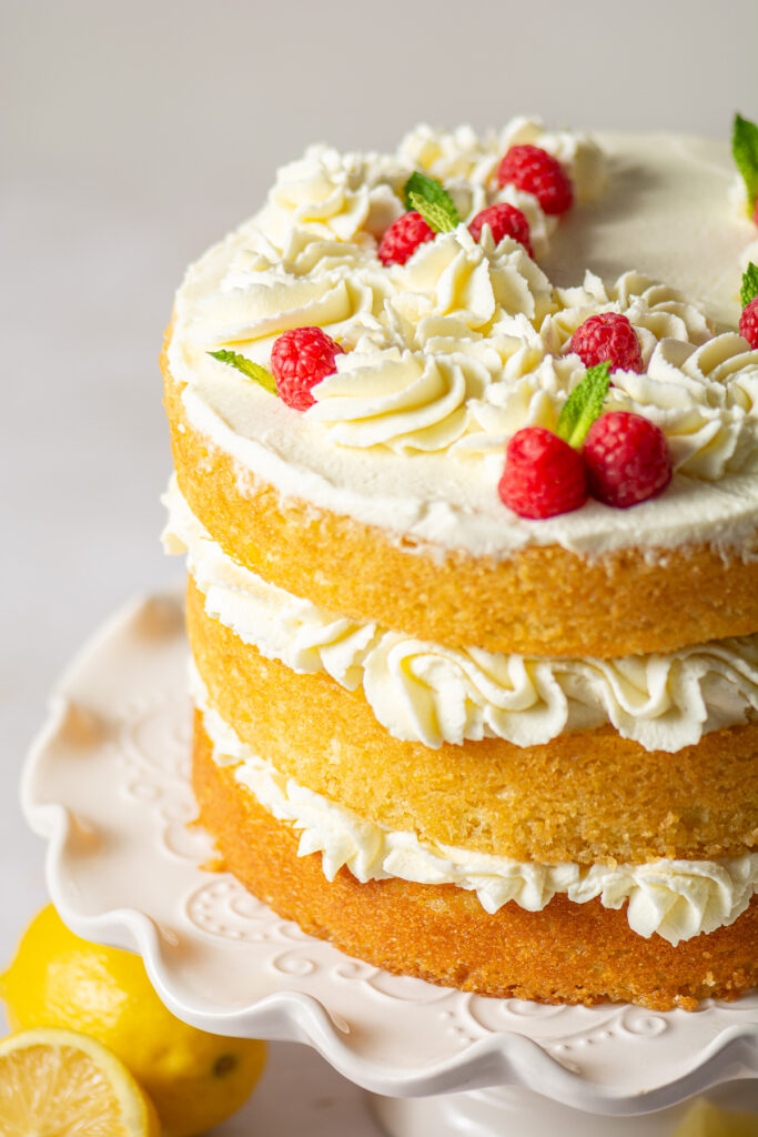 naked 3-layer honey lemon cake topped with mascarpone whipped cream rosettes, fresh raspberries and mint leaves