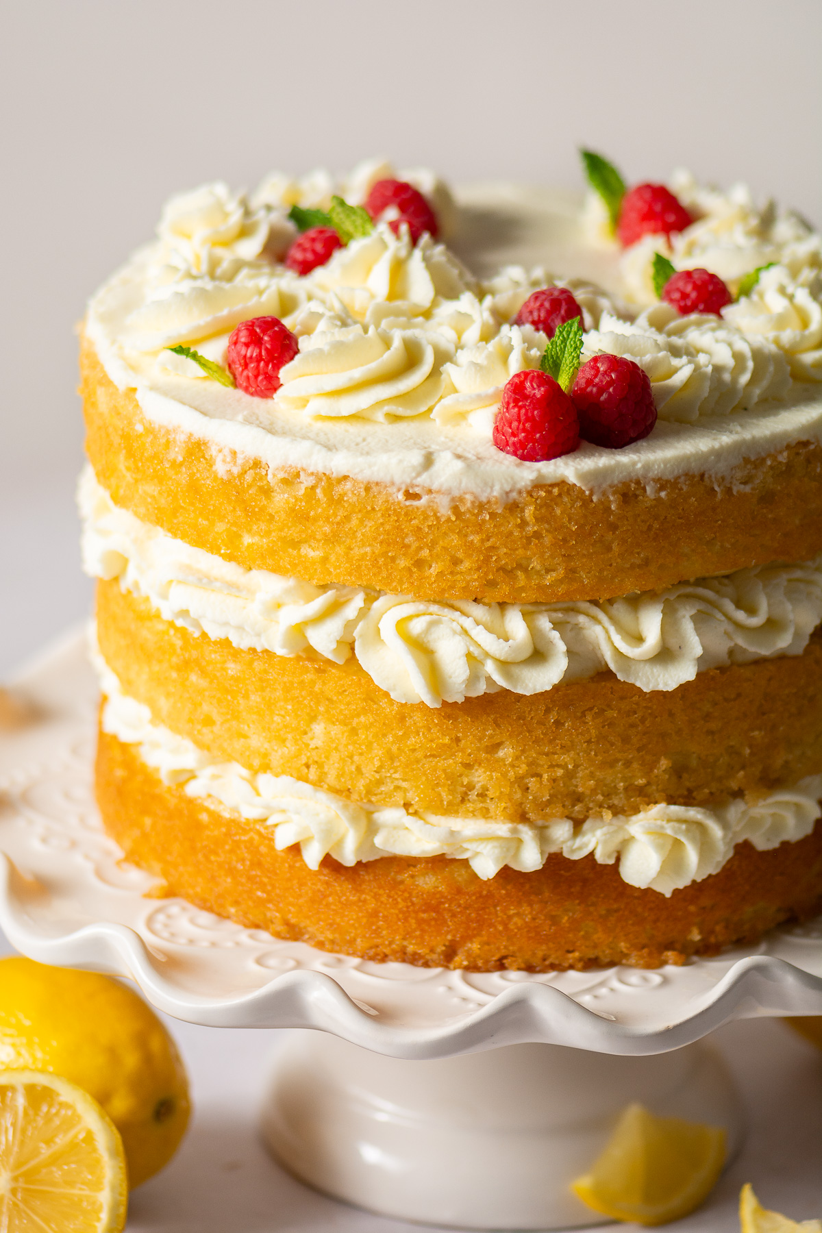 naked 3-layer honey lemon cake topped with mascarpone whipped cream rosettes, fresh raspberries and mint leaves