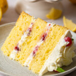 a slice of a 3-layer honey lemon cake showing mascarpone whipped cream and raspberry preserve filling