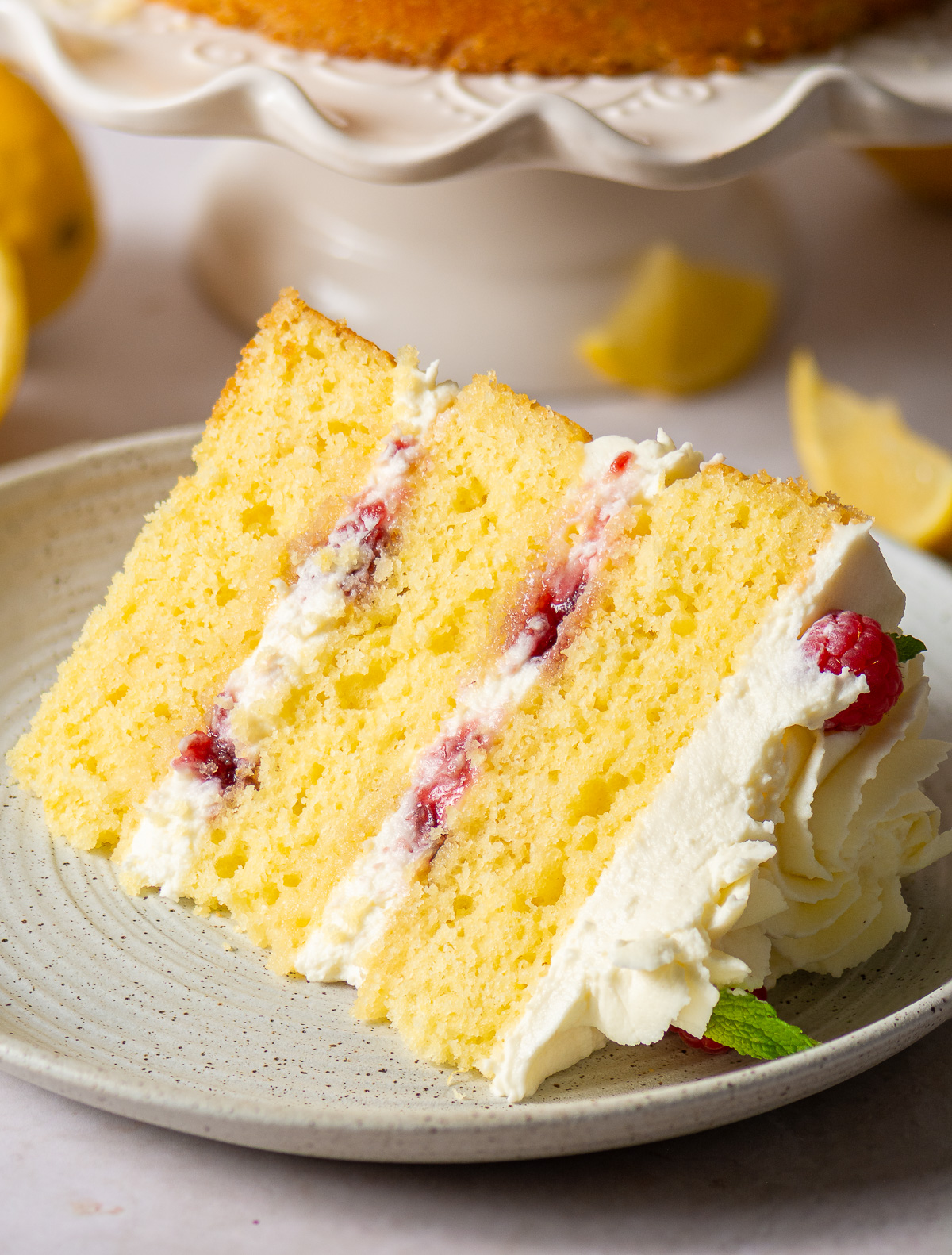 a slice of a 3-layer honey lemon cake showing mascarpone whipped cream and raspberry preserve filling
