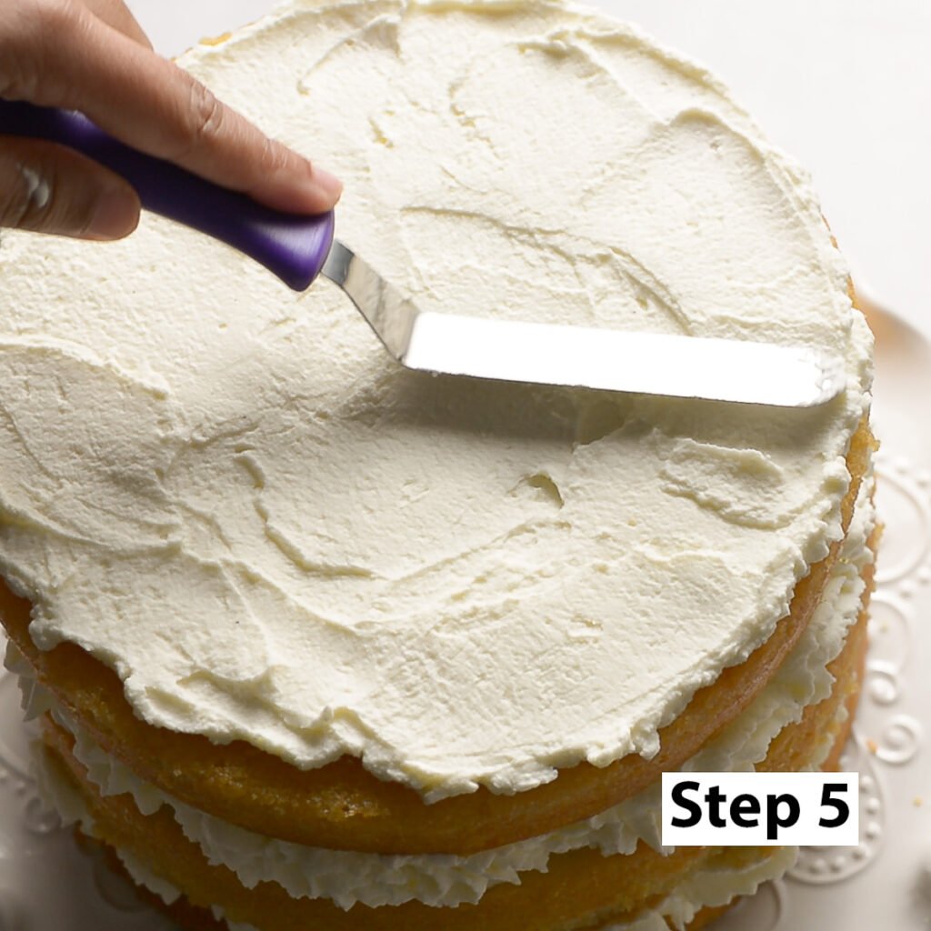 spreading whipped cream on top of a naked layer cake