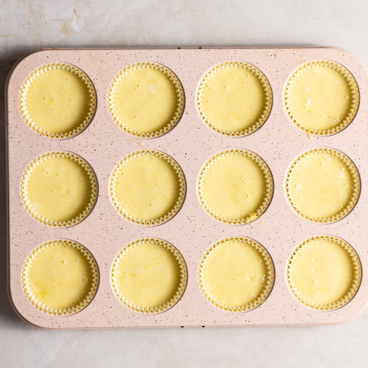 cupcake pan lined with baking cups and filled with lemon cupcake batter.