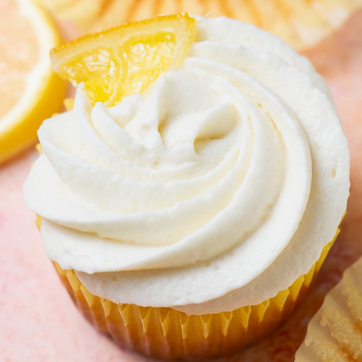 lemon cupcake with with cream cheese frosting and a candied lemon wedge.