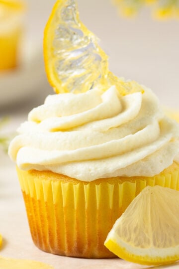 lemon cupcake topped with ermine cream cheese frosting and a candied lemon slice.
