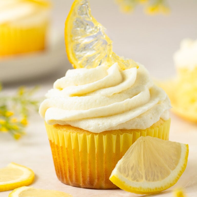 lemon cupcake topped with ermine cream cheese frosting and a candied lemon slice.