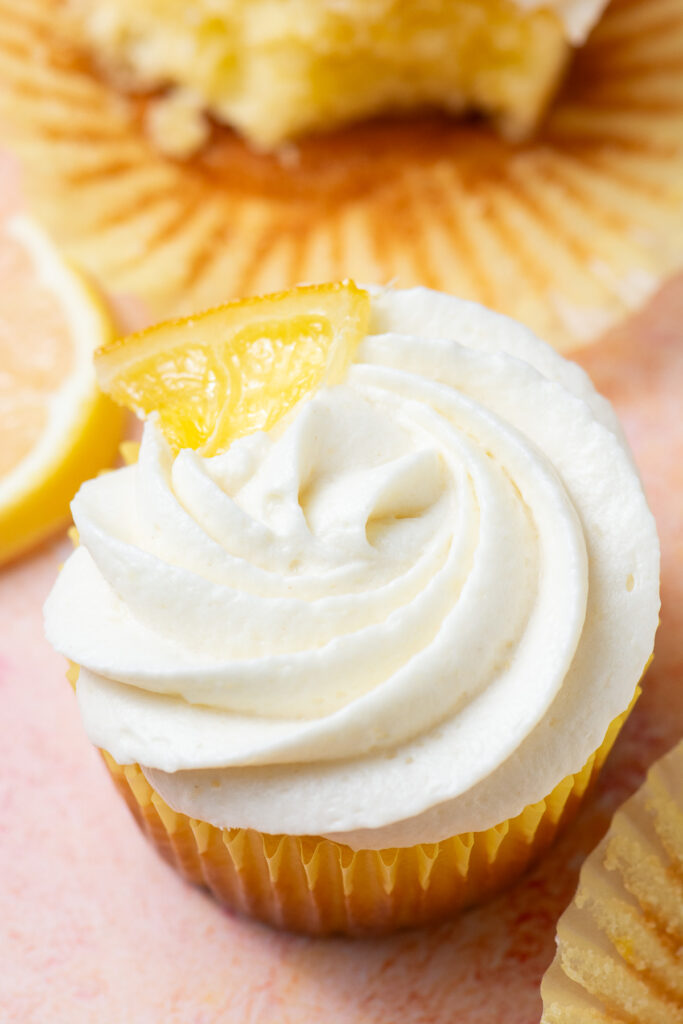 lemon cupcake topped with ermine cream cheese frosting and a candied lemon slice