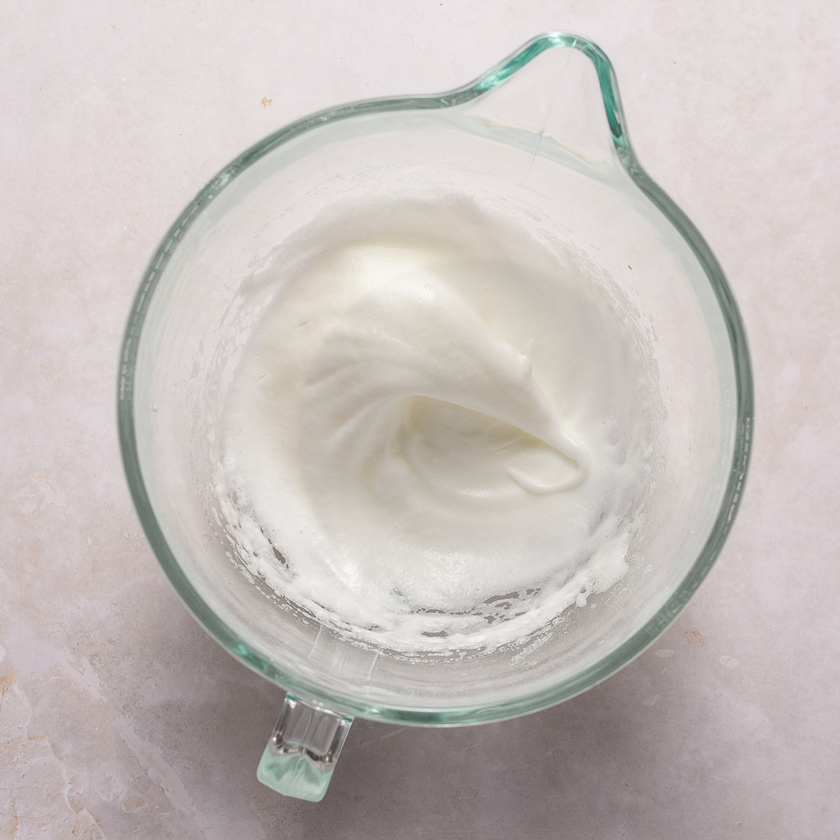 egg whites whipped to soft peaks in a glass bowl.