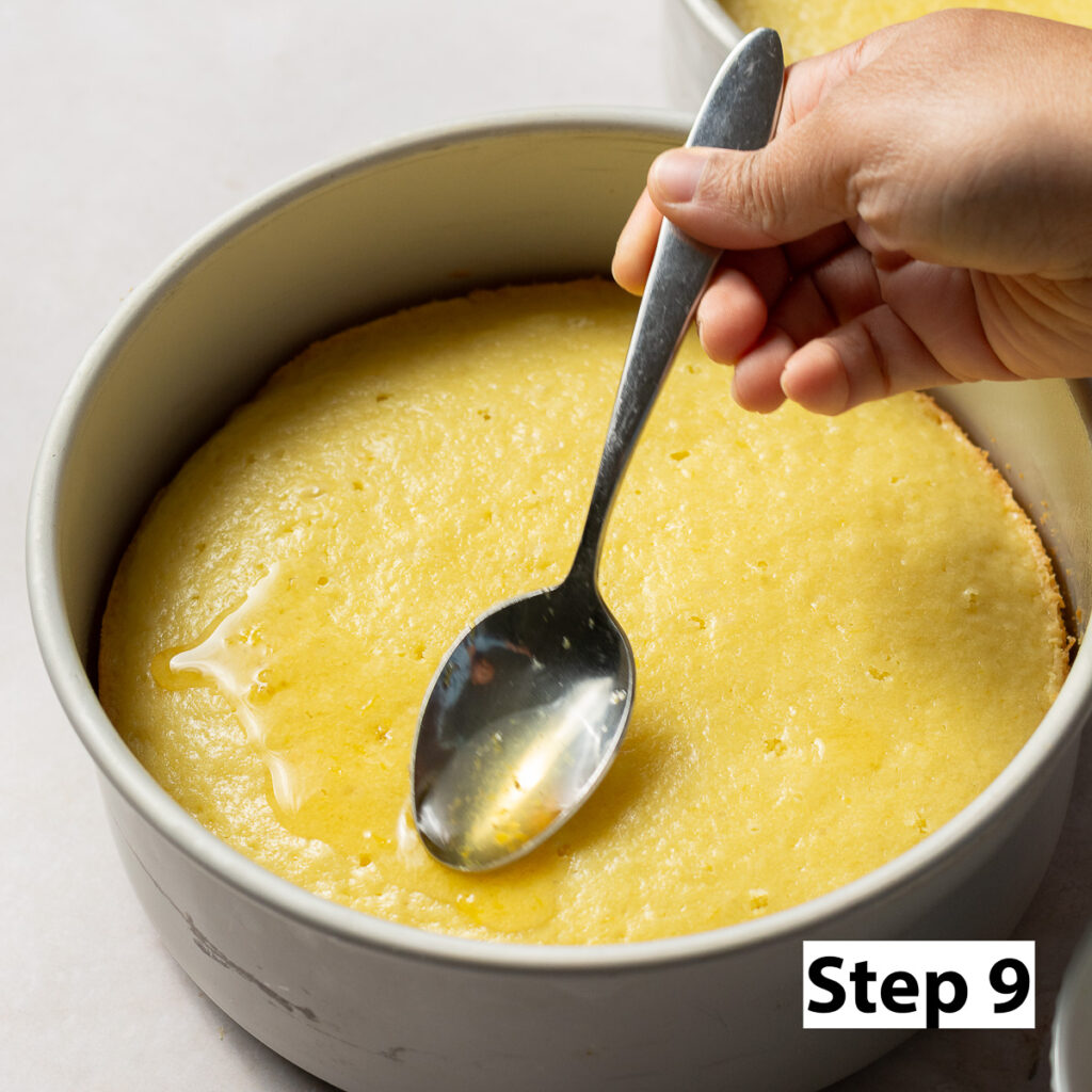 spooning honey lemon simple syrup onto honey lemon cake layers
