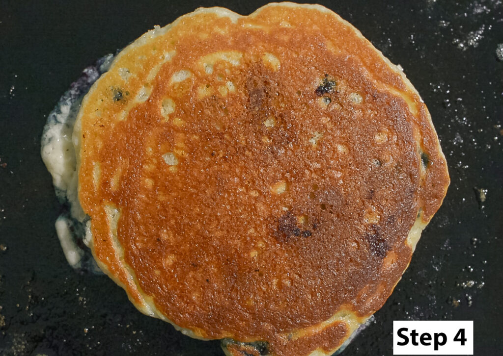 golden brown homemade blueberry pancake on a griddle