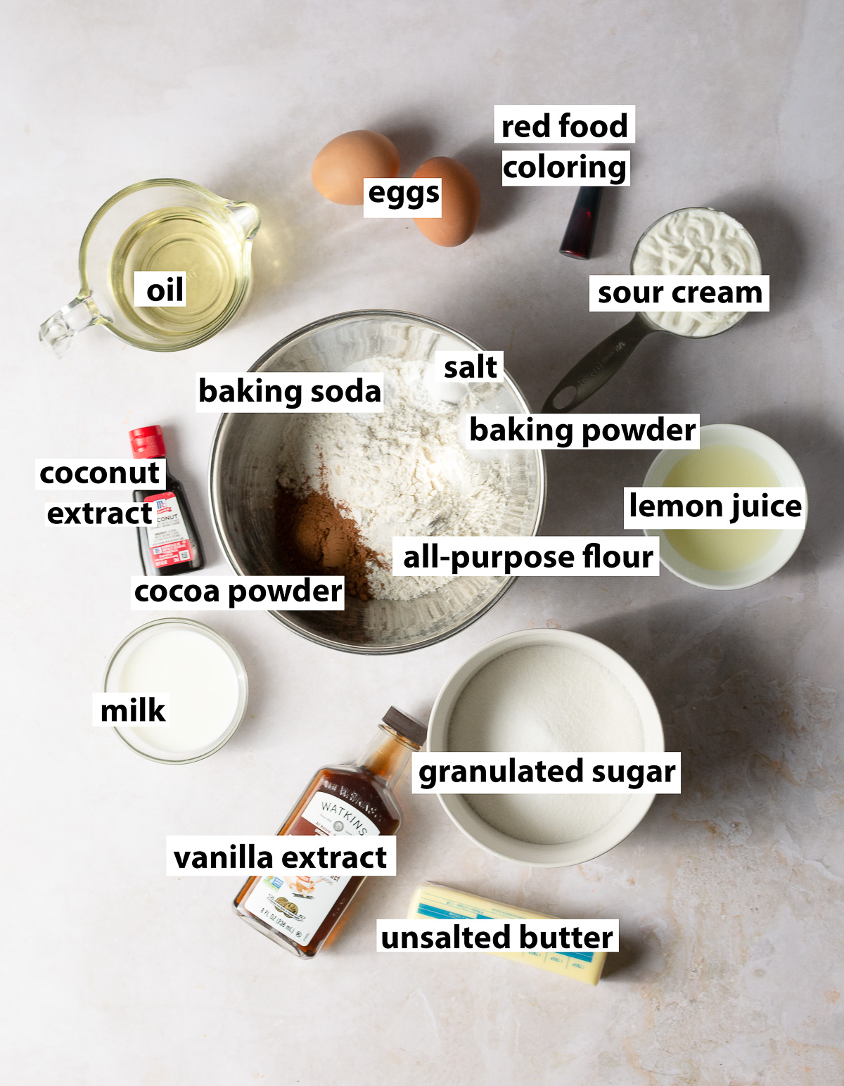 ingredients for red velvet cupcakes - all-purpose flour, cocoa powder, granulated sugar, sour cream, milk, lemon juice, baking soda, salt, baking powder, oil, unsalted butter, coconut extract, vanilla extract, red food coloring, eggs