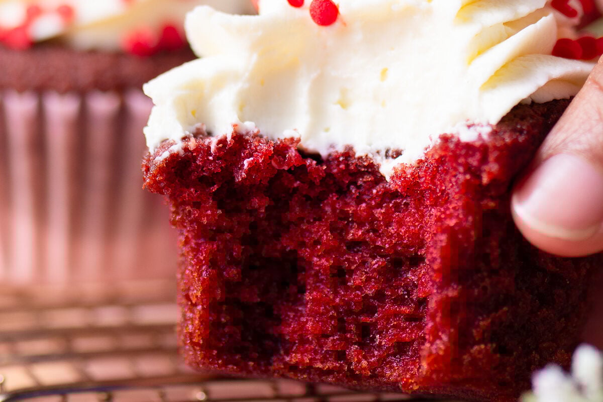 bitten red velvet cupcake with cream cheese frosting