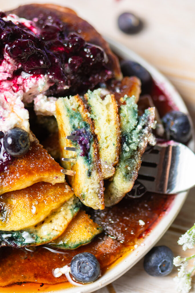 homemade blueberry pancakes on a fork with a little cool whip & blueberry compote topping and