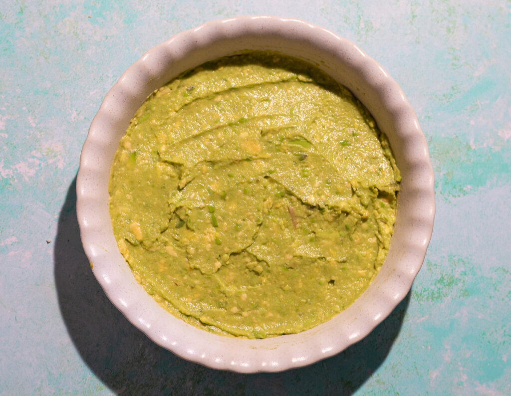 layering a Mexican dip in a pie dish with guacamole