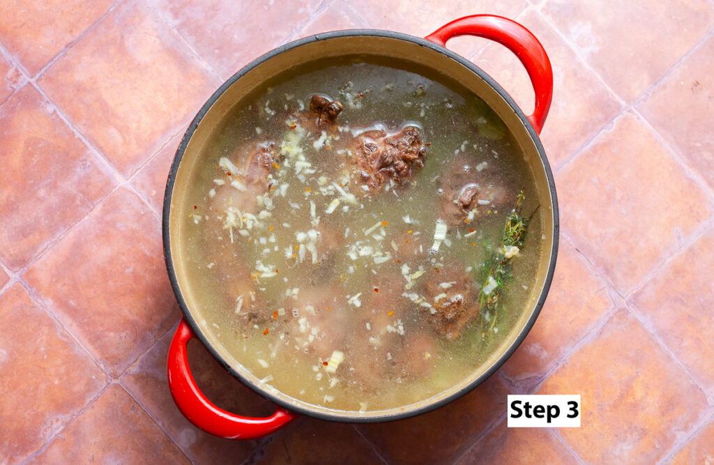 dutch oven filled water with smoked turkey necks, herbs and diced vegetables