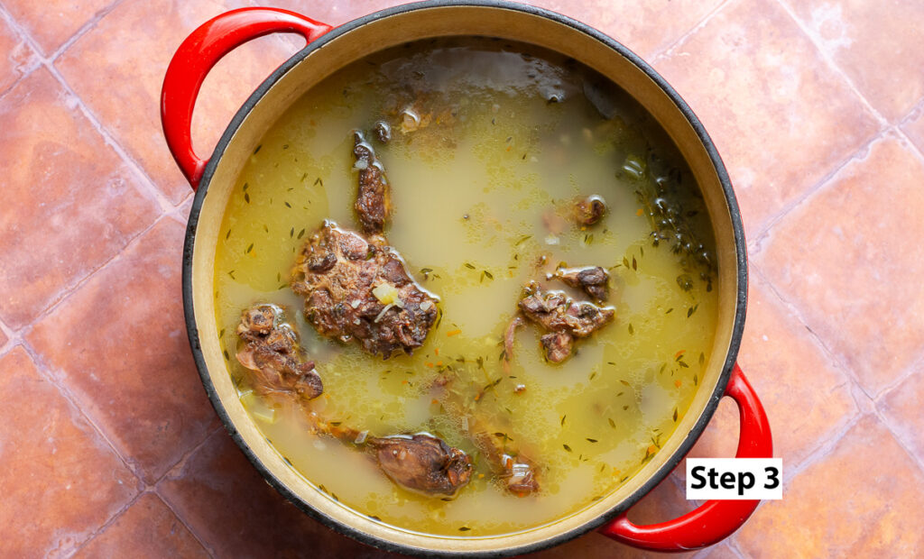 dutch oven filled water with smoked turkey necks, herbs and diced vegetables