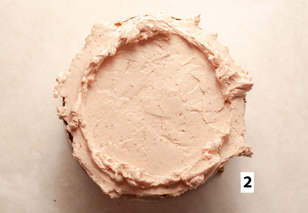 a layer of strawberry Swiss meringue buttercream on top of a strawberry cake layer with well in the center