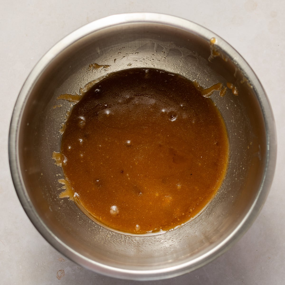melted butter and sugar in a stainless steel mixing bowl.