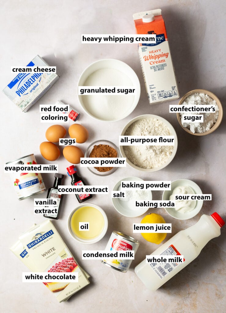 ingredients for red velvet cheesecake tres leches - all-purpose flour, granulated sugar, cocoa powder, eggs, baking powder, baking soda, salt, vanilla extract, coconut extract, red food coloring, sour cream, oil, lemon juice, whole milk, evaporated milk, condensed milk, heavy whipping cream, cream cheese, confectioner's sugar and white chocolate