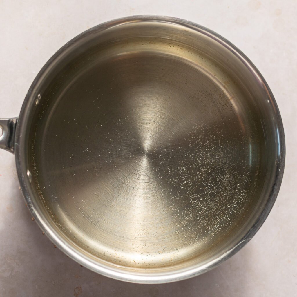 hot water in a stainless steel pot with tiny bubbles on the bottom of pot