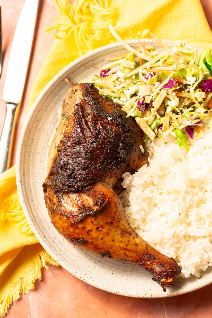 jerk chicken on a plate with white rice and salad