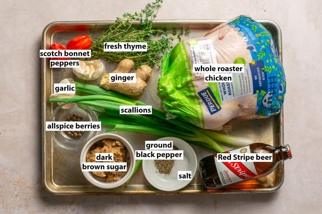 ingredients for authentic Jamaican jerk chicken - whole roaster chicken, fresh thyme, scotch bonnet peppers, scallions, garlic, ginger, allspice berries, dark brown sugar, ground black pepper, salt & red Stripe beer