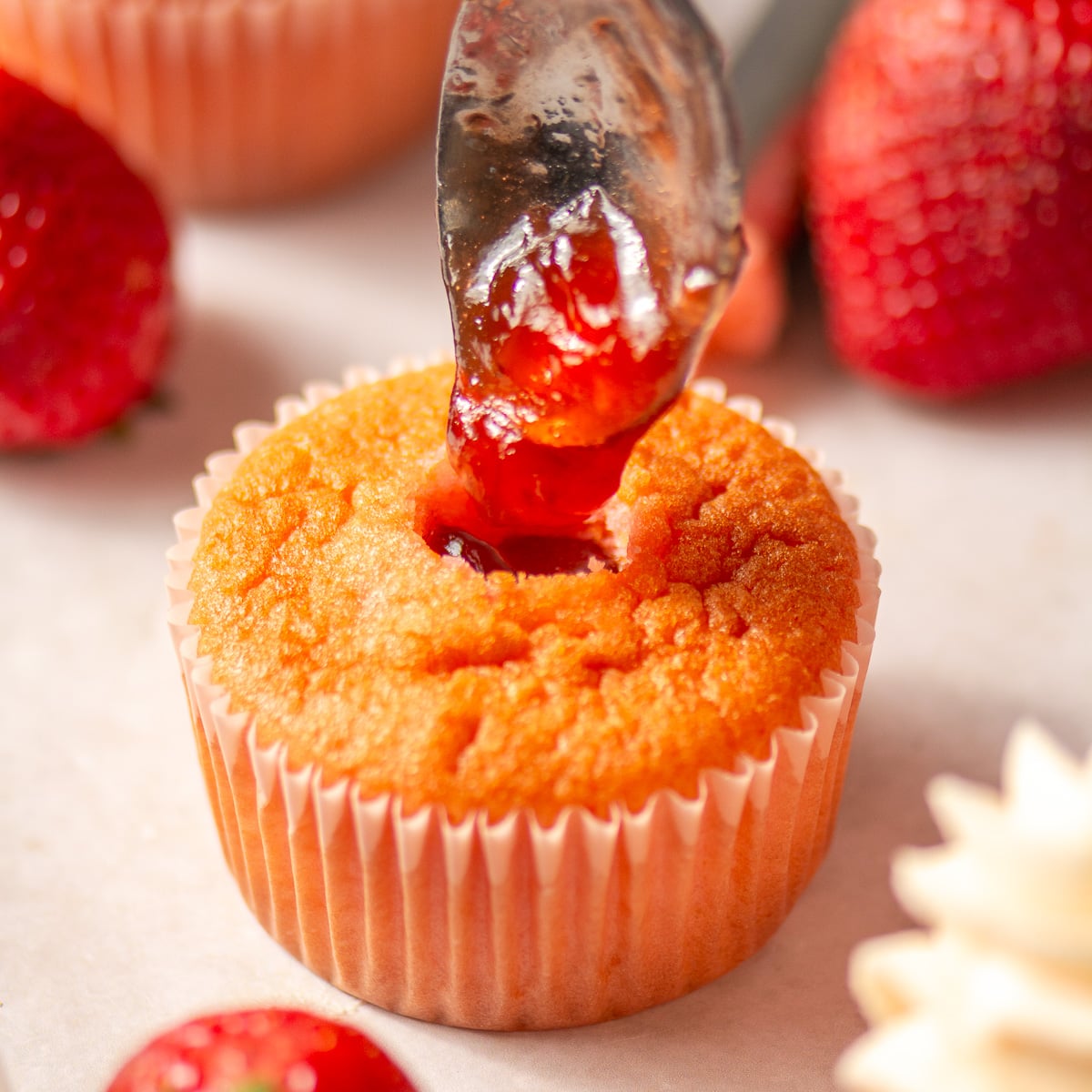 filling strawberry cupcakes with strawberry preserves.