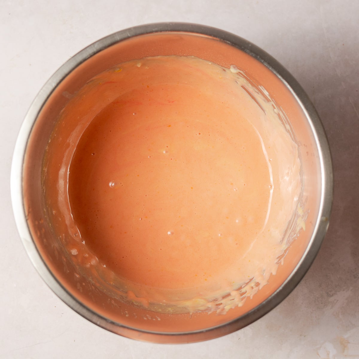 dry ingredients mixed with strawberry milk, egg yolks, oil and food coloring in a bowl.