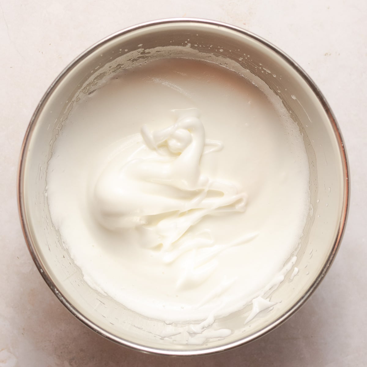 egg whites whipped to firm peaks in a stainless steel bowl.